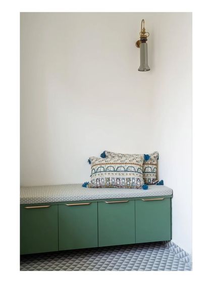A shoe storage bench on the private balcony, continuing the olive green color scheme. The patterned flooring pays homage to the Spanish theme, creating a charming and functional outdoor nook.