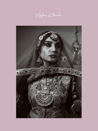 A dramatic portrait with the bride's face partially veiled. This black and white image emphasizes the ornate, traditional jewelry and the rich texture of her bridal wear.