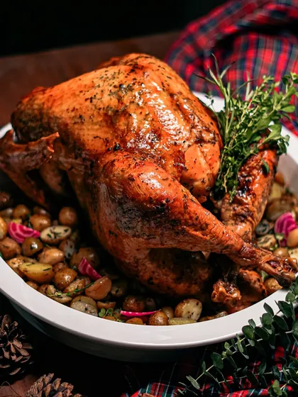 Another stunning shot of our whole roasted turkey, resting on a bed of roasted potatoes and herbs. We take the stress out of holiday cooking by delivering this masterpiece to your door.