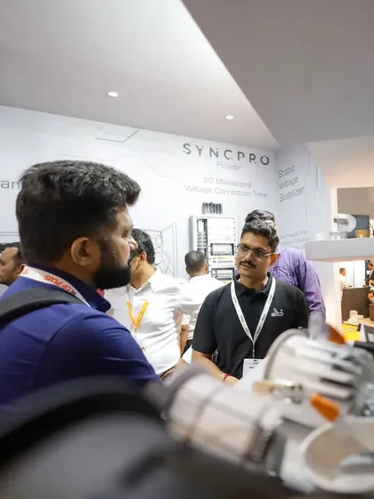 An over-the-shoulder view at our expo booth, where a team member discusses our technology with a visitor, with some of our lighting hardware visible in the foreground.
