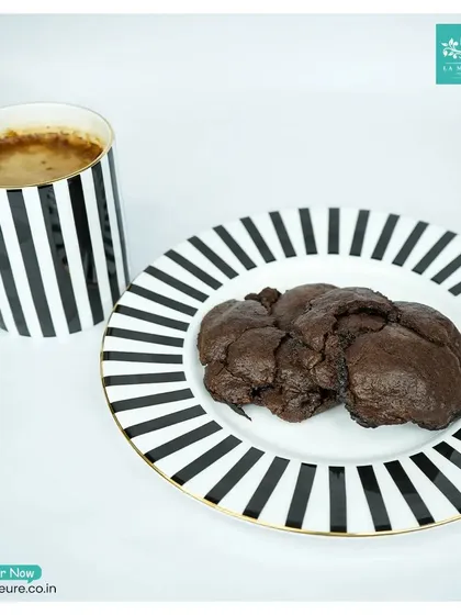 Our rich, dark chocolate cookies served on a plate next to a cup of coffee. It's the perfect pairing for a relaxing break.