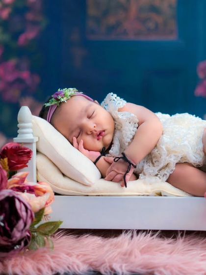 A sleeping beauty in a garden of flowers. This newborn girl looks so peaceful sleeping on a tiny bed, surrounded by beautiful floral arrangements.