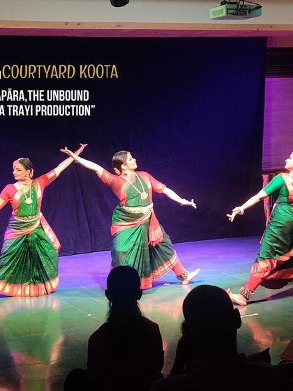 A performance of 'Apāra, The Unbound', a Trayi production. The three dancers are captured in a moment of powerful, synchronized movement, showcasing the beauty of group choreography.