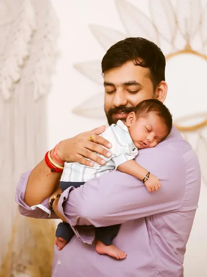 There's a special bond between a father and his newborn. This portrait captures that tender connection, with the baby sleeping peacefully on his father's shoulder.
