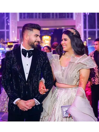 A candid shot of the couple sharing a happy moment on the dance floor. Their smiles and the vibrant lighting of the reception venue create a lively and joyful image.