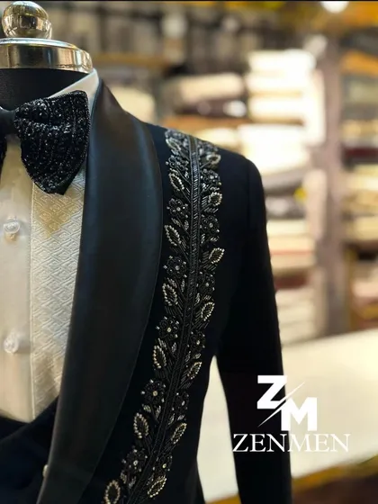 A close-up of a black tuxedo with silver leaf motifs embroidered along the lapel. The craftsmanship is evident in every stitch and bead.