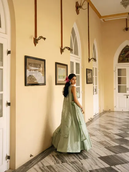 A wide shot capturing the model in a heritage corridor, showing the scale of the architecture and the flow of her gown. This image helps build the aspirational world of the brand.