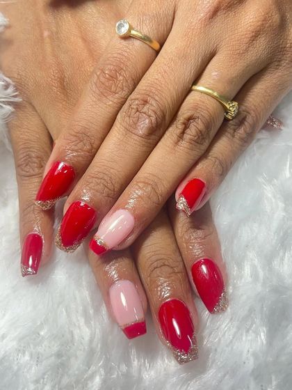 A still image of the red and glitter French tip nails. The contrast between the vibrant red and the sparkling silver tips is very eye-catching.