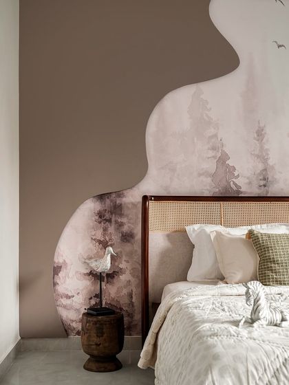This versatile guest room doubles as a kids' room, designed with a mature yet playful vibe. The highlight is a stunning wallpaper mural of a misty forest, creating a dreamy and imaginative backdrop for the cane headboard.