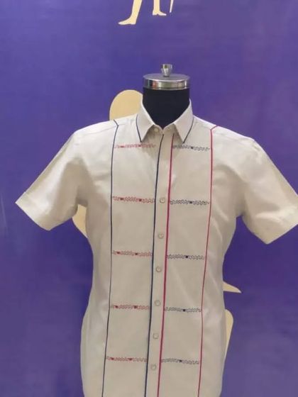 A custom half-sleeve shirt with geometric embroidery. The red and blue threadwork adds a pop of color to the white shirt, making it a unique and stylish piece.