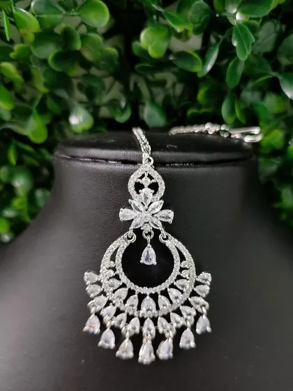 A delicate AD maang tikka with a floral top and dangling crystals, perfect for a modern bride.