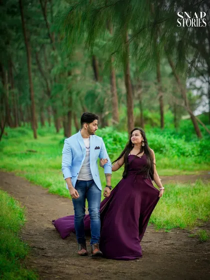 A beautiful shot of a couple walking along a dirt path surrounded by lush green trees, perfect for a nature-themed pre-wedding photoshoot.