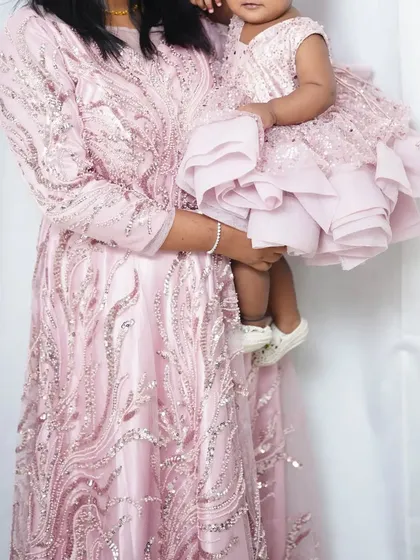 This baby pink mother-daughter gown set is perfect for a first birthday photoshoot. The intricate silver sequin work adds a touch of sparkle to your special day.