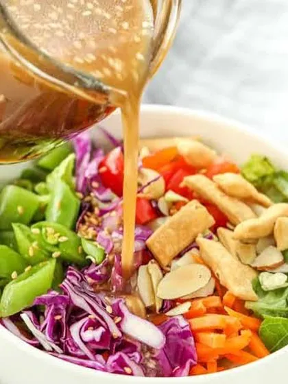 My Asian Honey Sesame dressing being poured over a fresh salad. I make all my dressings from scratch without any preservatives, offering a healthy and delicious alternative to store-bought options.