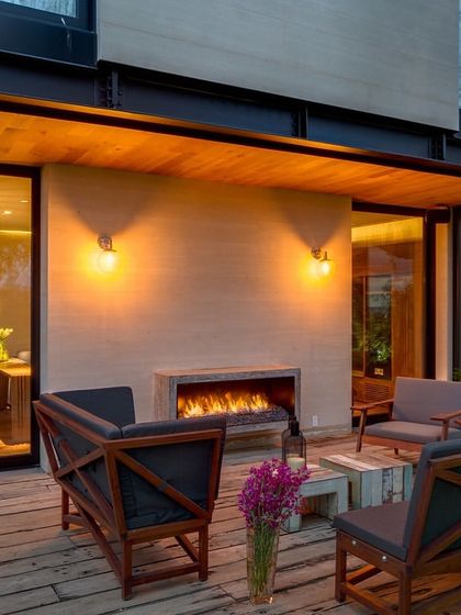 This backyard balances structure with nature. The minimal design of the seating area, complete with an outdoor fireplace, has a rustic edge that creates a space that feels grounded and inviting.