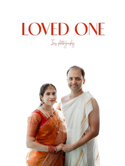 A studio portrait of a couple dressed in traditional attire for a naming ceremony. The simple, bright background keeps the focus on the couple's happy and proud expressions.