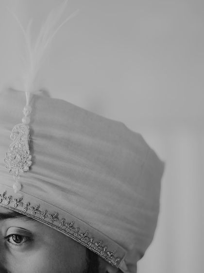 An intense and artistic close-up of the groom's eye, with his turban and its feather detail beautifully framed. This monochrome shot is powerful and full of character.
