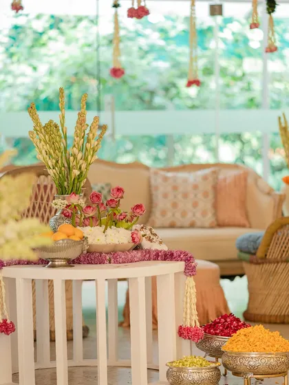A beautiful indoor Mehendi setup, transforming the space with pastel lounges, marigold accents, and traditional garlands for a "pooja to party" vibe.