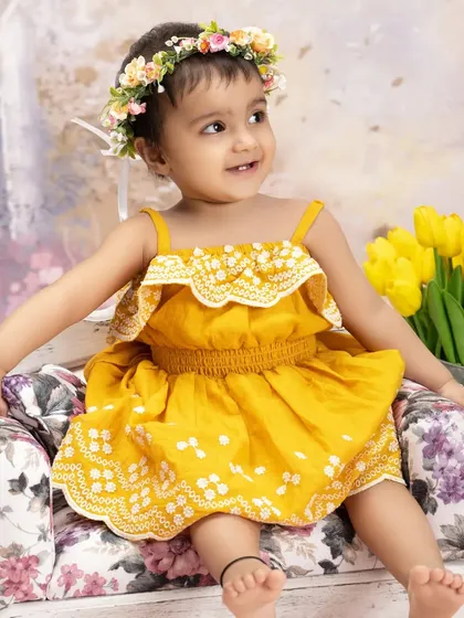 Sunshine in a yellow dress. This little girl's bright smile and floral crown are perfectly complemented by the vibrant yellow tulips in our spring garden set.