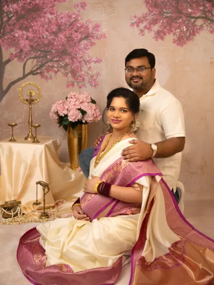 An elegant couple poses for a traditional maternity portrait in my studio, with the mother-to-be glowing in a beautiful silk saree.