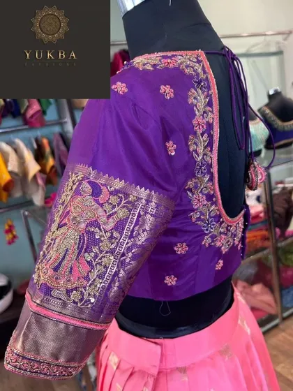 A side view of a purple blouse paired with a pink skirt. The sleeve features a beautiful embroidered motif of a woman, showcasing my ability to create personalized story-telling designs.