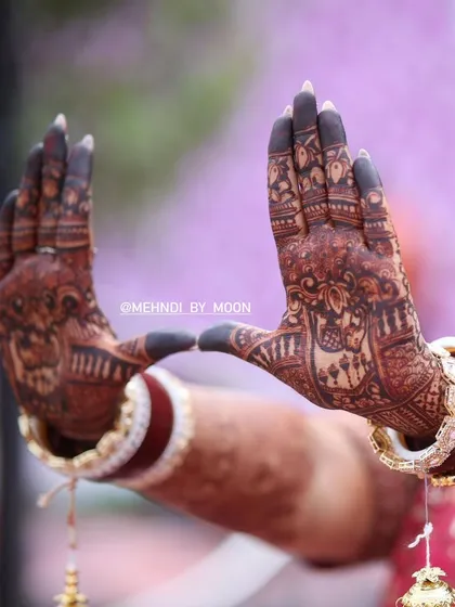 A focused shot on the beautiful dark stain of the bridal mehndi. The contrast between the filled fingertips and the detailed patterns on the palm is a classic bridal look.