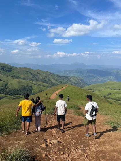 Four trekkers walking along the scenic path of Netravathi peak, showcasing the journey and the destination.