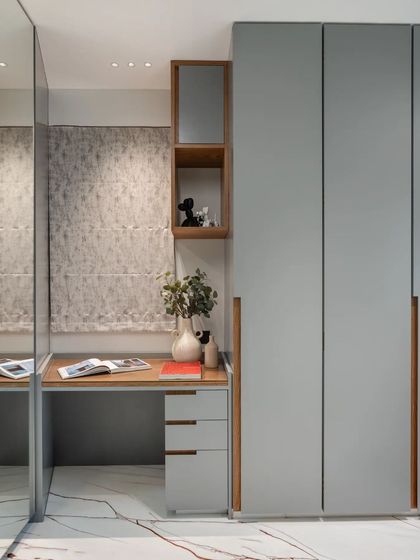 This compact study and wardrobe area in the son's room is designed for efficiency. A mirrored wardrobe door enhances the sense of space, while the wooden desk and shelving nook provide a warm, dedicated zone for work and storage.