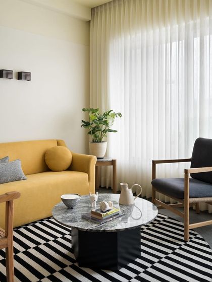 A full view of the living room, where the custom yellow sofa brings warmth and personality. I design seating to be the heart of a room, combining comfort with a strong design statement.