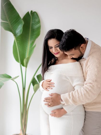 A tender moment between a couple during their studio maternity session, filled with warmth and anticipation.