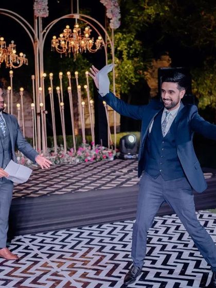 The groom's performance on a custom black-and-white geometric dance floor. The stage backdrop features elegant chandeliers and modern light installations, creating a stylish setting for sangeet performances.