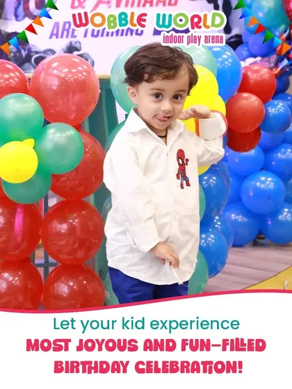 A young boy in a Spiderman shirt enjoying his birthday party, surrounded by colorful balloons and decorations.