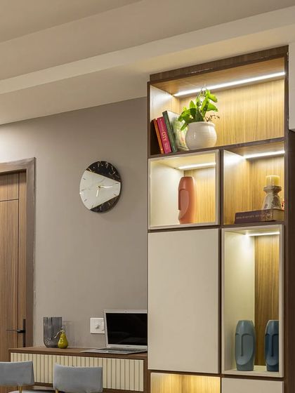This image showcases a custom-built shelving unit that doubles as a compact workspace. The integrated lighting highlights the display objects, while the design provides a practical solution for homes needing a dedicated work-from-home area.