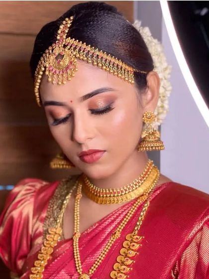 Sharmila looking gorgeous for her big day. This is a classic South Indian bridal look with soft brown and gold eye makeup, a defined lip, and traditional temple jewellery, including a beautiful matha patti.