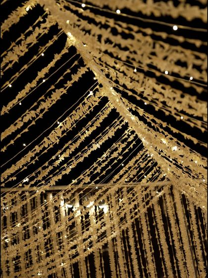 A detail of the ceiling installation, where thousands of white floral strings were interwoven with fairy lights to create a magical, starry sky effect.