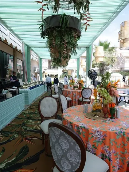 A view of the buffet and dining area, showing the long, shaded canopy decorated with hanging plants and woven lanterns.