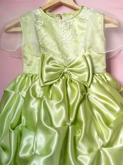 A closer look at the craftsmanship of this lime green party dress. The oversized satin bow and carefully gathered bubble skirt are details that create a truly unique and memorable garment.