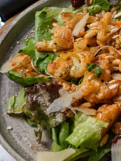 A closer look at my signature roasted cauliflower salad. Tossed with pine nuts and parmesan shavings over a bed of fresh greens, it's a healthy and flavorful option for any event.