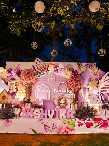 Nishvika's magical garden of dreams, a beautiful fairy-themed setup under the stars. The purple fairy house is lit from within, surrounded by glowing mushrooms, butterfly wings, and fairy cutouts.