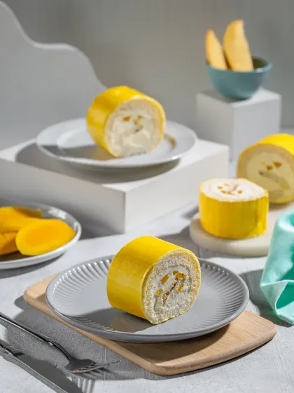 A bright and airy composition of mango Swiss rolls, deconstructed to show the creamy filling and fresh fruit, perfect for a summer menu feature.