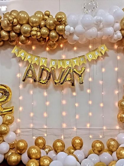 A beautiful gold and white balloon frame decoration for a 12th birthday at home, complete with a fairy light curtain.
