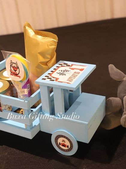 A single blue truck hamper next to its cuddly elephant companion, ready for a little one's birthday.