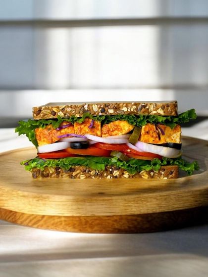 Our Homemade Paneer Tikka Sandwich is a classic for a reason. It features soft, marinated paneer tikka, crisp lettuce, onions, and tomatoes on multigrain bread. It’s a taste of home, made healthy.