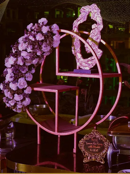Artful decor as a centerpiece for our food display. This circular stand adorned with a cascade of purple flowers adds a touch of modern artistry to the buffet.
