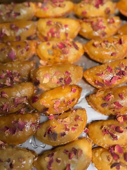 A close-up of my OG Gujiyas, glistening with syrup and sprinkled with rose petals. A traditional festive treat, handcrafted with love.