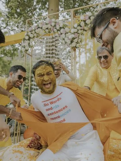 The groom's friends get mischievous, pulling at his shirt during the Haldi, a moment of pure, unscripted fun.