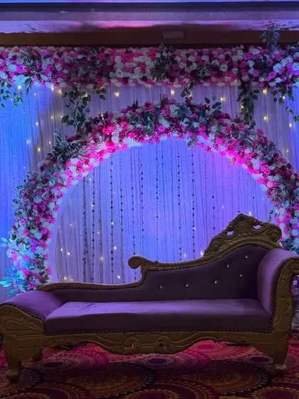A simple yet elegant stage for an engagement or ring ceremony. I used a floral arch against a backdrop of white curtains and fairy lights, with a classic purple chaise lounge as the centerpiece.