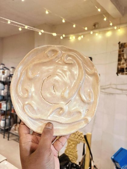 A student's hand-built plate with beautiful, fluid swirls. This piece shows a wonderful exploration of texture and form, created during her beginner's course.