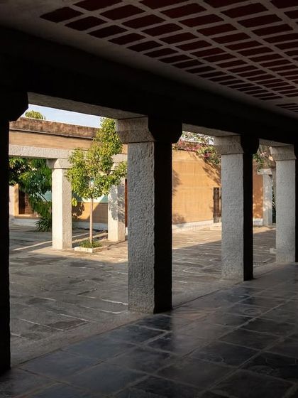 A colonnaded walkway at the H.N. Science Center, with granite pillars supporting a filler slab roof. This transitional space provides shade and frames views of the central courtyard.