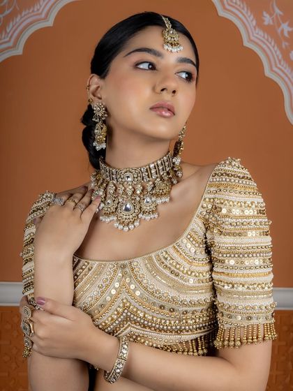 This royal choker set, paired with statement bangles and rings, showcases the beauty of traditional craftsmanship. The intricate details and pearl drops create a look of pure elegance for a bride's grand entrance.